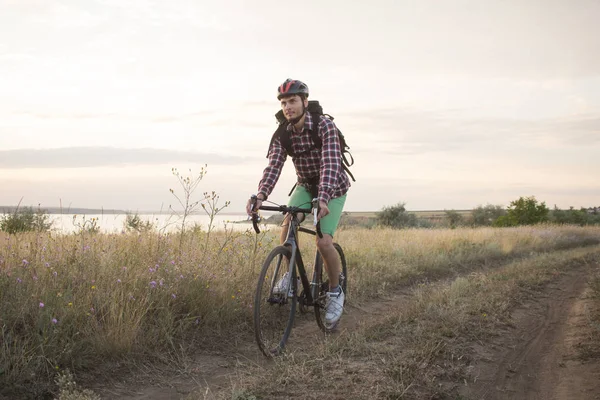 Bicycle Touring on the country road in summer fields