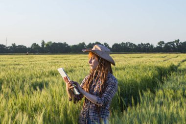 Tablet ellerde ile çiftçi iş genç kadın buğday alanları