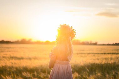 kafası güzel sarışın Bayan çiçek çelenk gündoğumu sırasında yaz buğday alanlarında