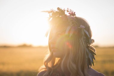 kafası güzel sarışın Bayan çiçek çelenk gündoğumu sırasında yaz buğday alanlarında