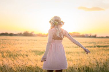 kafası güzel sarışın Bayan çiçek çelenk gündoğumu sırasında yaz buğday alanlarında
