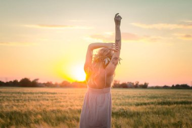 kafası güzel sarışın Bayan çiçek çelenk gündoğumu sırasında yaz buğday alanlarında