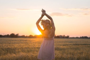 kafası güzel sarışın Bayan çiçek çelenk gündoğumu sırasında yaz buğday alanlarında