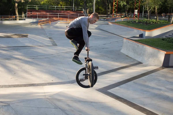 BMX rider training and do tricks in street plaza, bicyxle stunt rider in cocncrete skatepark