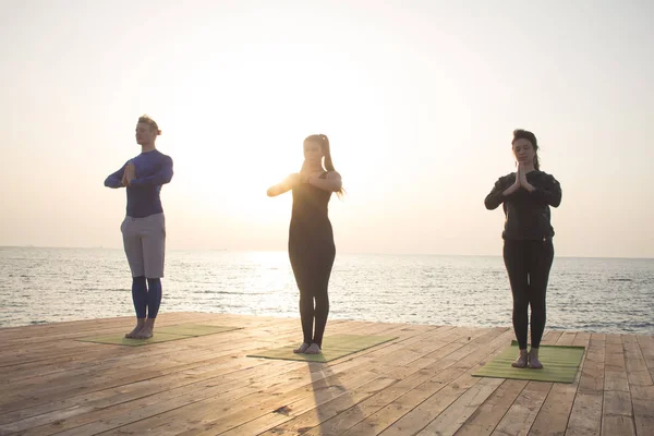 Grupul Oameni Din Yoga Pozează Stand Cheiul Lemn Răsăritul Soarelui — Fotografie, imagine de stoc