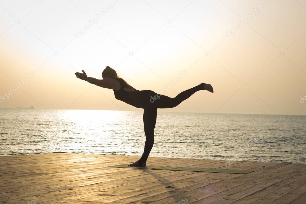 Portrait og fit young woman in yoga pose on the morning beach