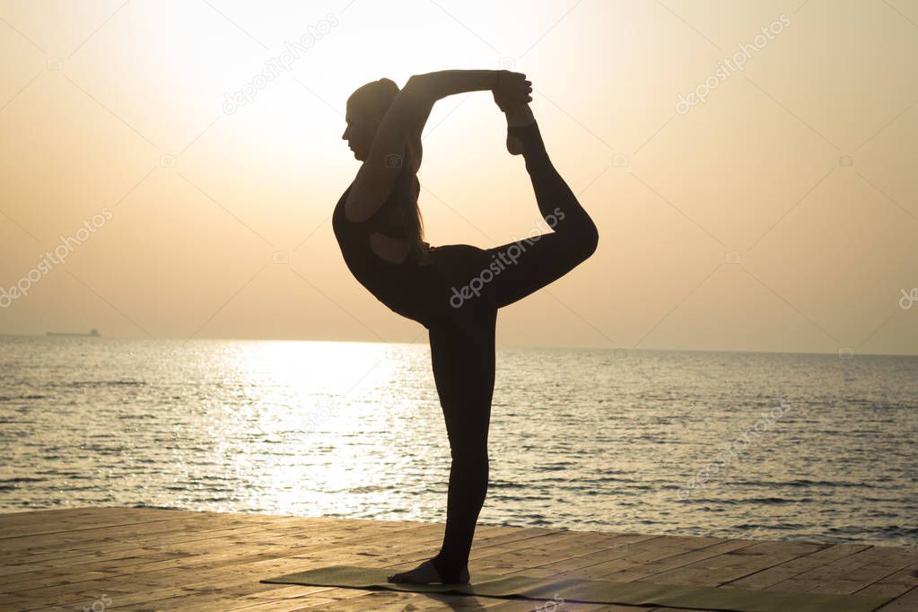 Portrait og fit young woman in yoga pose on the morning beach