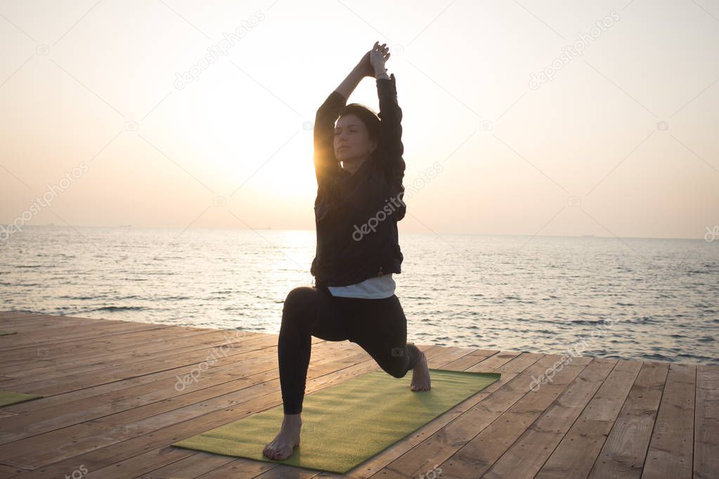 Portrait og fit young woman in yoga pose on the morning beach