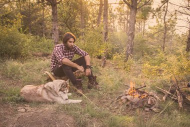 Halk veya ülke gitar çalan köpek sahip, adam woods, kamp ateşi ve gün batımı arka plan