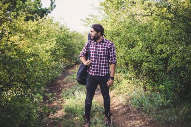 Genç erkek uzun saç ve gitar, ormanda hiking gezgin müzisyen portresi ile sakallı 