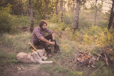 Halk veya ülke gitar çalan köpek sahip, adam woods, kamp ateşi ve gün batımı arka plan