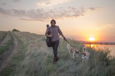 gitar ve göl günbatımı sırasında husky köpek uçurumdaki genç yakışıklı erkekler