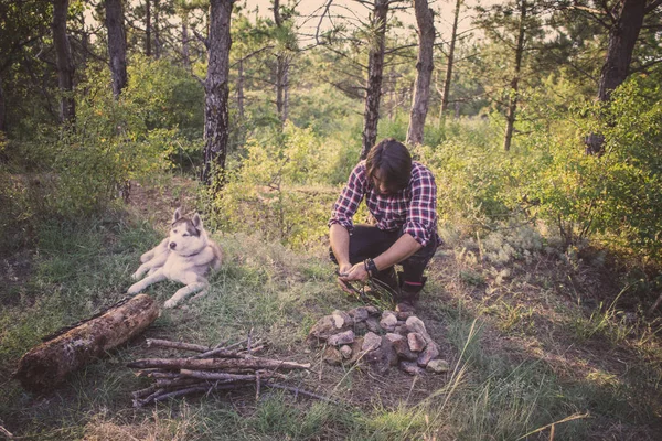 Halk veya ülke gitar çalan köpek sahip, adam woods, kamp ateşi ve gün batımı arka plan