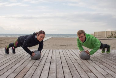 Gençler açık havada eğitim grup, sporcular birkaç koşucular yapmak egzersizleri, deniz veya nehir arka plan
