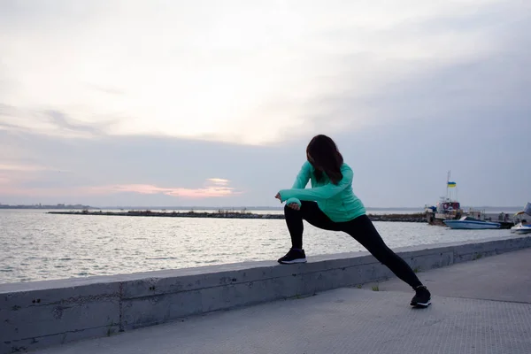 young woman do stretching exercises, sunrise in sea background