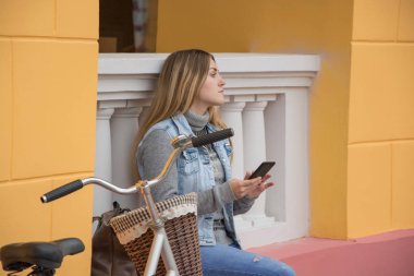 Genç kadın bisiklet binici kullanım cep telefonu, kentsel arka plan