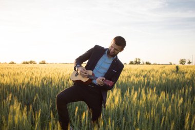 Ukulele seyahat yaz buğday alanları ile mutlu müdür, buisinesman takım elbise oynamak ukulele, tatil veya seyahat kavram resmi için