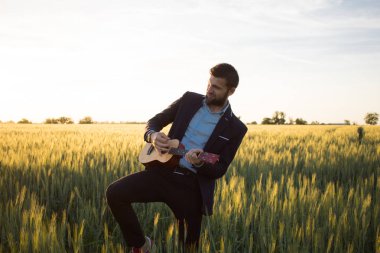 Ukulele seyahat yaz buğday alanları ile mutlu müdür, buisinesman takım elbise oynamak ukulele, tatil veya seyahat kavram resmi için