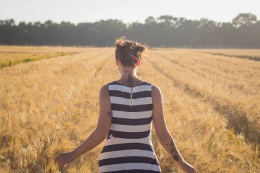 Rahatlatıcı ve yaz buğday alanlarında iyi vakit geçiren genç mutlu kadın 