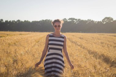 Rahatlatıcı ve yaz buğday alanlarında iyi vakit geçiren genç mutlu kadın 