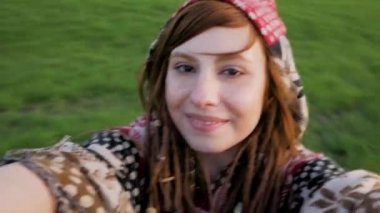 Selfie dönüyor etrafında, dreadlocks ile mutlu hippi kız portresi ve yeşil alanlara güneşli günü alarak genç Kızıl saçlı kadın portresi