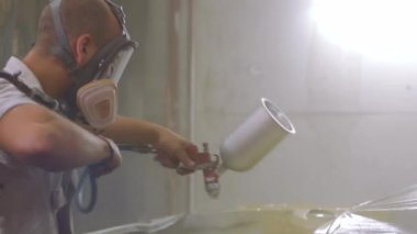 Araba boyama atölyesinde, işçi maskesi kullanın boya tabancası garajda.