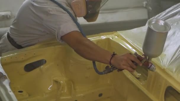 Processus de peinture de voiture en atelier, travailleur dans le pistolet de pulvérisation d'utilisation de masque dans le garage .