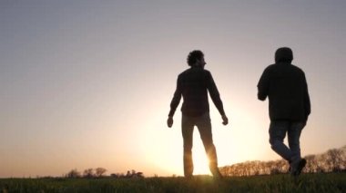 koşma, atlama ve having fun bahar alanlarında, gün batımı arka plan iki genç halk silüeti