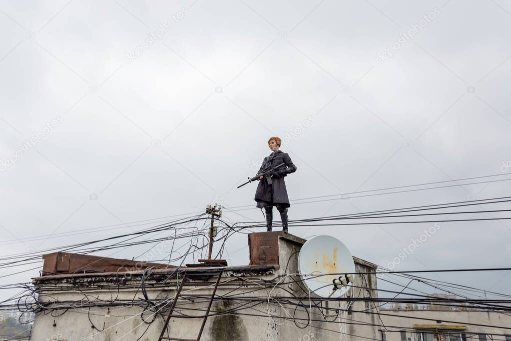 Young woman in modern black techwear style with rifle posing on the rooftop, portrait of redhead woman cyperpunk or   post apocalyptic concept