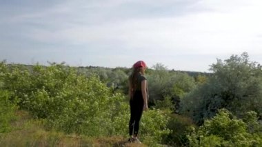 Genç kadın üstünde belgili tanımlık tepe yaz güneşli bir günde, dağ orman arka plan poz