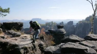 Genç kadın gezgin dağlarda uçurumdaki sırt çantası standlı