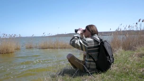 Молодий Чоловік Рюкзаком Біноклем Відпочиває Біля Річки Сонячний День — стокове відео