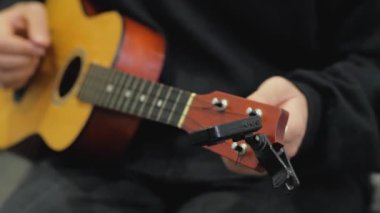Ukulele üzerinde elektronik Tuner ile ayarlama ve oynama süreci yakın yukarı