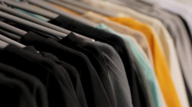Dükkanda bir askı üzerinde birçok t-shirt yakın