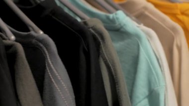 Dükkanda bir askı üzerinde birçok t-shirt yakın
