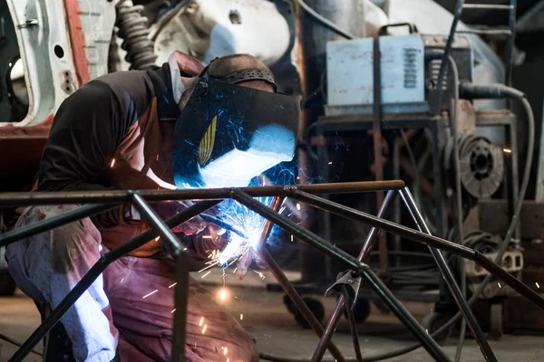 Workers in the mask are welding steel in workshop