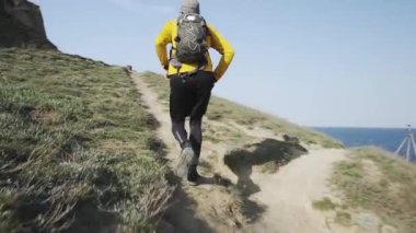 Güneşli bir gün tepede sırt çantası eğitimi ile genç erkek Trail Runner