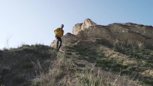 晴れた日の丘の上にバックパックのトレーニングと若い男性トレイルランナー — ストック動画
