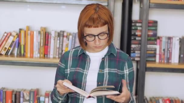 Молода Руда Жінка Окулярах Читає Книгу Бібліотеці — стокове відео