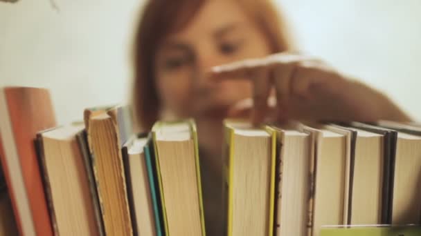 Junge Frau Wählt Bücher Regal — Stockvideo