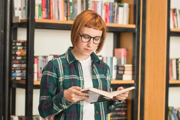 Młoda Ruda Kobieta Okularach Czytać Książkę Bibliotece — Zdjęcie stockowe