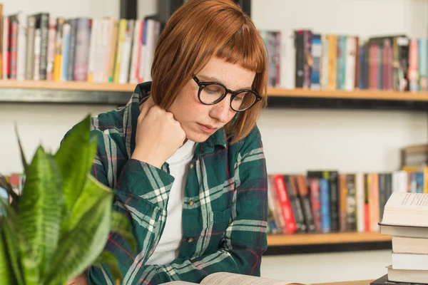 Młoda Ruda Kobieta Okularach Czytać Książkę Bibliotece — Zdjęcie stockowe