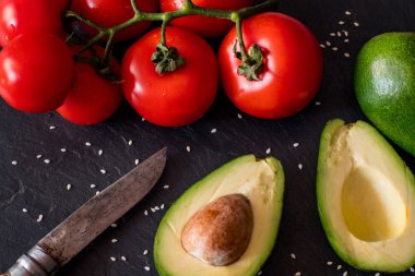 Domates ve avokado siyah masada yakın, renkli sağlıklı gıda 