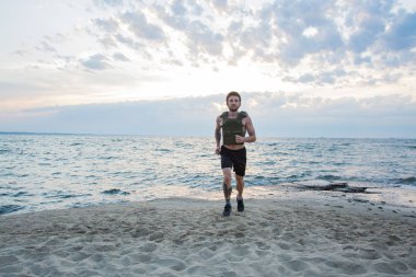 Genç sakallı atlet ağırlıklı yelek ile açık havada eğitim, askeri plaka taşıyıcı ile egzersiz