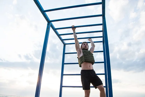 Young bearded athlete training outdoor with weighted vest,  exercise with military plate carrier