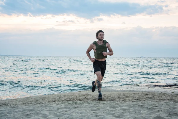 Young bearded athlete training outdoor with weighted vest,  exercise with military plate carrier