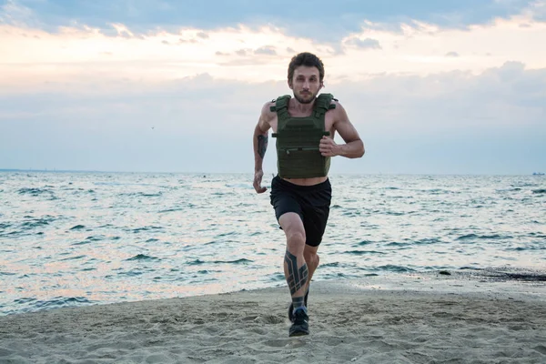 Young bearded athlete training outdoor with weighted vest,  exercise with military plate carrier