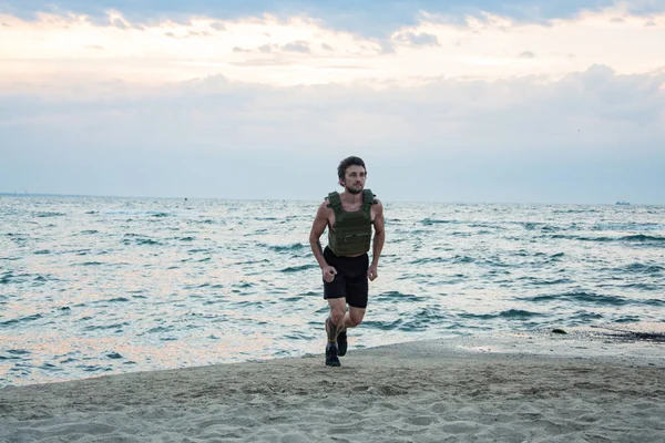 Young bearded athlete training outdoor with weighted vest,  exercise with military plate carrier