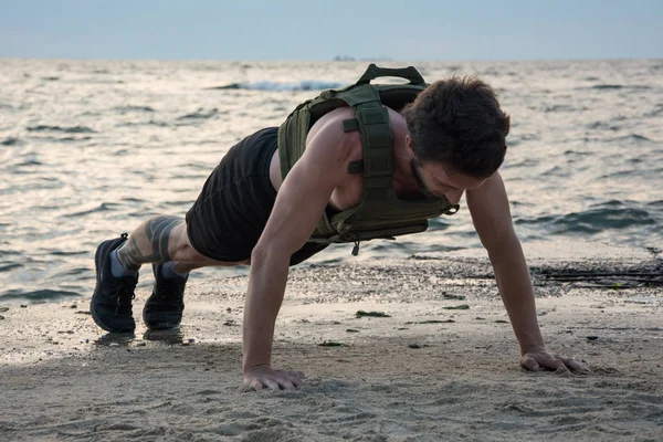 Young bearded athlete training outdoor with weighted vest,  exercise with military plate carrier