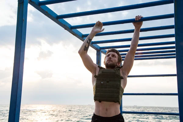 Young bearded athlete training outdoor with weighted vest,  exercise with military plate carrier